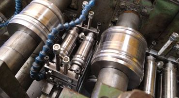 Close-up of industrial metal rollers and bolts in machinery.