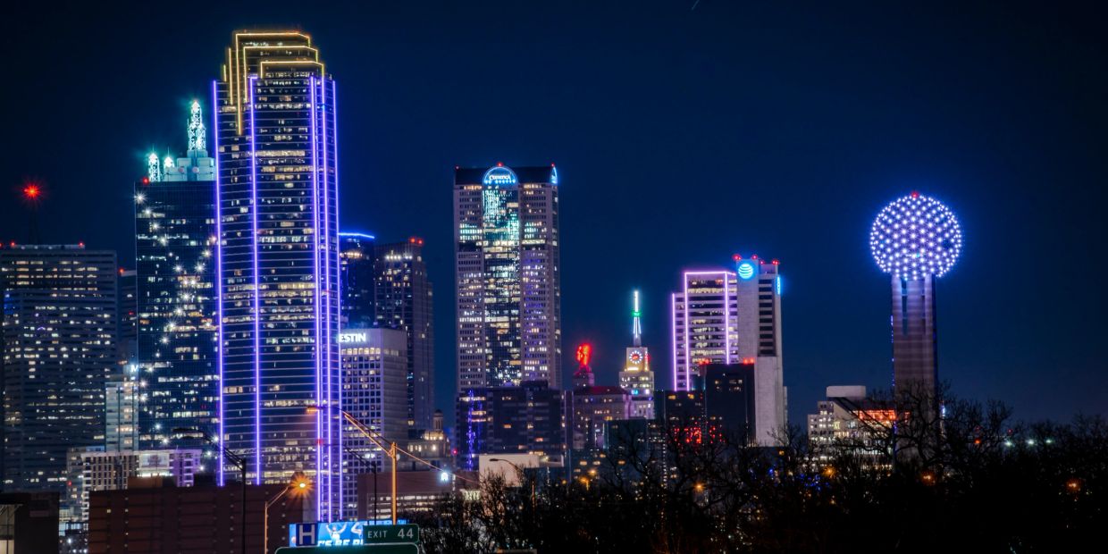 Nighttime cityscape with illuminated skyscrapers and a glowing spherical tower.
