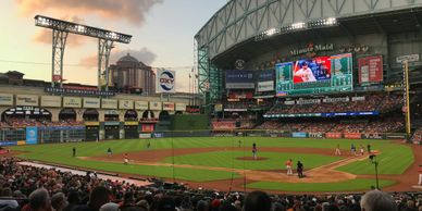 A baseball game at a large stadium during sunset.