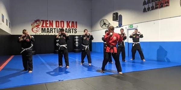 A group of men in a martial arts studio in front of a sign.