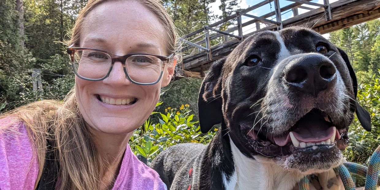Woman and dog smiling outdoors.