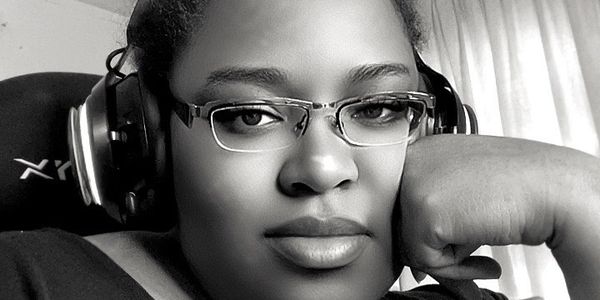 Black and white portrait of a woman wearing cat ear headphones and glasses.