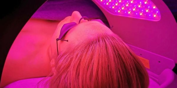 Person wearing protective goggles under red LED light therapy.