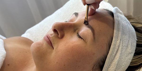 Woman getting eyebrow makeup applied with a brush during a beauty treatment.