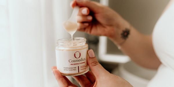 Hands holding a jar of O Cosmedics Pumpkin Enzyme &amp; Fruit Acid Peel.