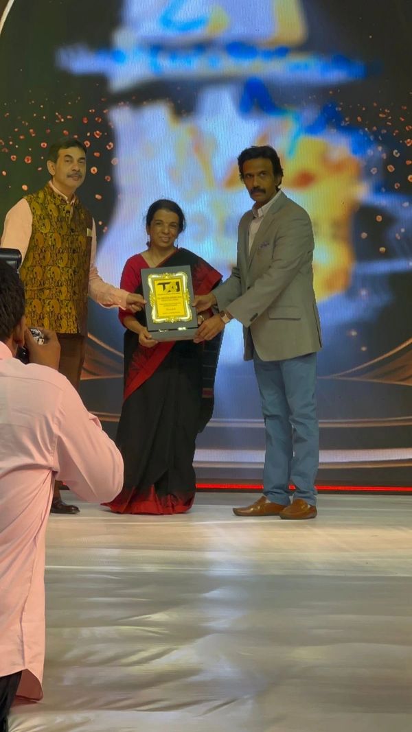 Three people on stage holding a plaque during an award ceremony.