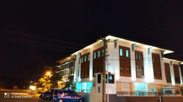 Illuminated building at night with parked cars in front.
