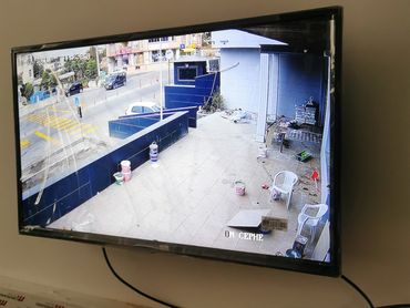 TV screen showing an outdoor security camera feed of a street and patio area.