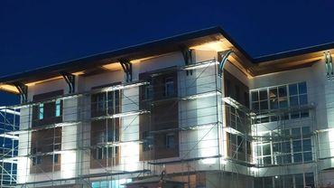 Modern building illuminated at night with large windows and architectural details.