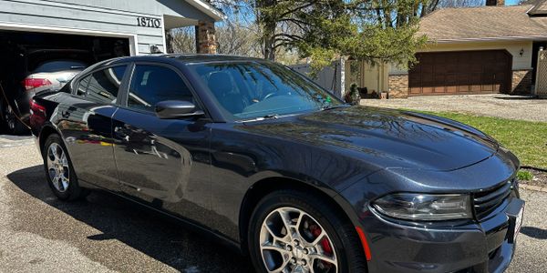 Sleek dark gray Dodge Charger parked in a sunny residential driveway.