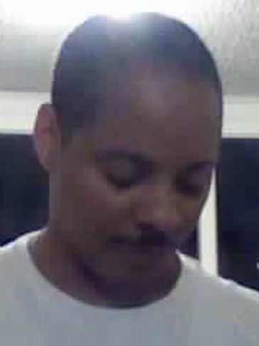 Man with mustache looking down in a room with a window.