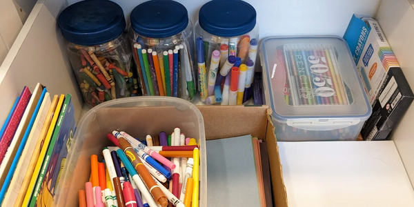 Open drawer showing organized kids craft supplies in unique recycled containers