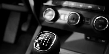 Close-up of a car's manual gear shift knob in black and white.