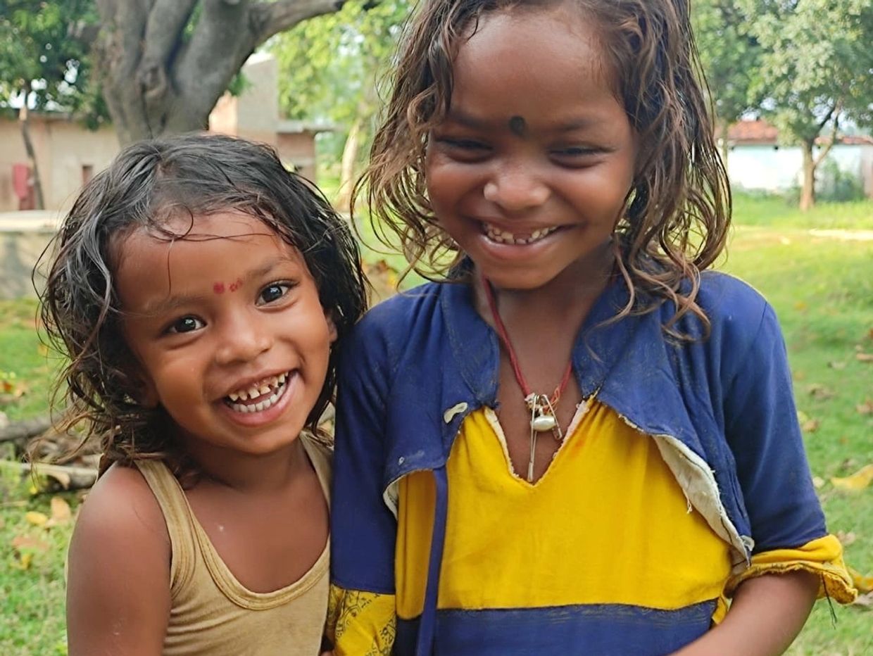 Two smiling children enjoying a sunny day outdoors.