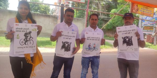 Four people holding posters promoting environmental awareness and cycling.