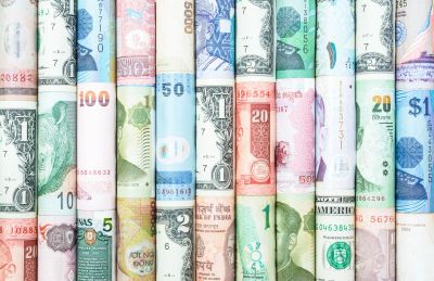 Rolled banknotes of various currencies lined up.