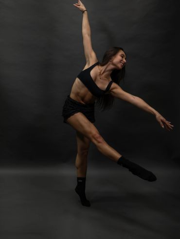 Woman dancing gracefully against a dark background.