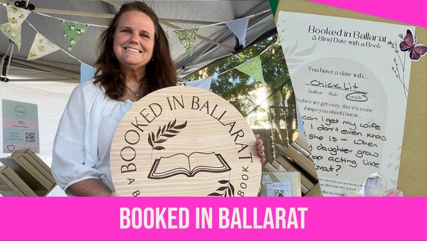 Woman holding a wooden sign for Booked in Ballarat event.