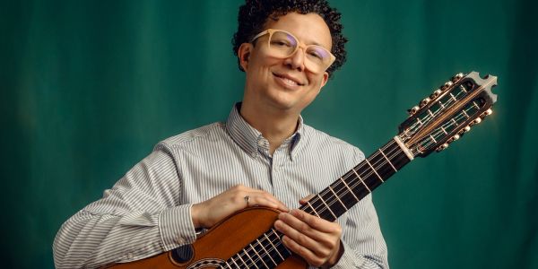 Man holding a guitar and smiling.