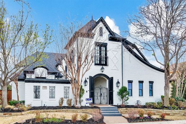 White Tudor-style house with black trim and landscaped front yard.