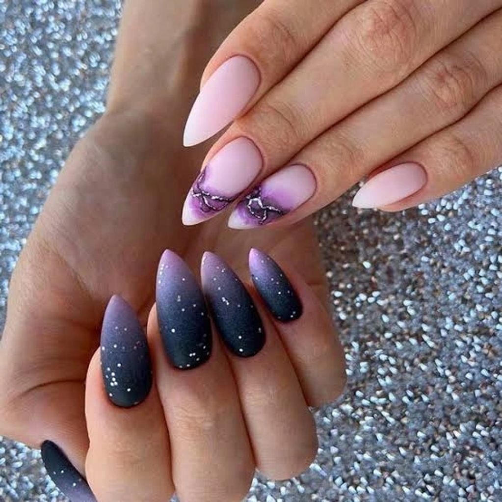 Elegant matte ombré purple and black stiletto nails with white speckles and silver chain accents.