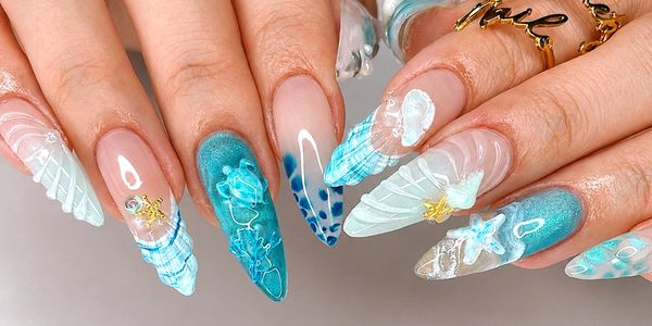 Blue and white ocean-themed acrylic nails with 3D shells and starfish.