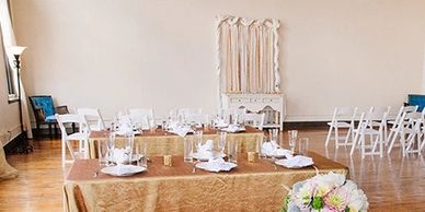 Elegant banquet setup with gold tablecloth and floral centerpiece.
