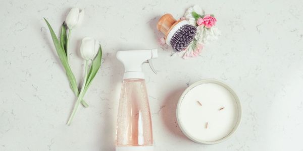 Flat lay of cleaning and floral items on a marble surface.
