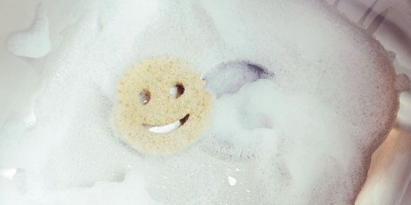 Smiley face sponge in bubbly, foamy water.