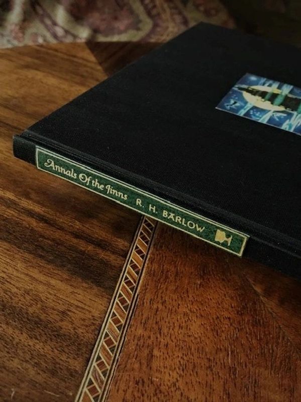 A book titled 'Annals Of the Inns' by R. H. Barlow on a wooden table.