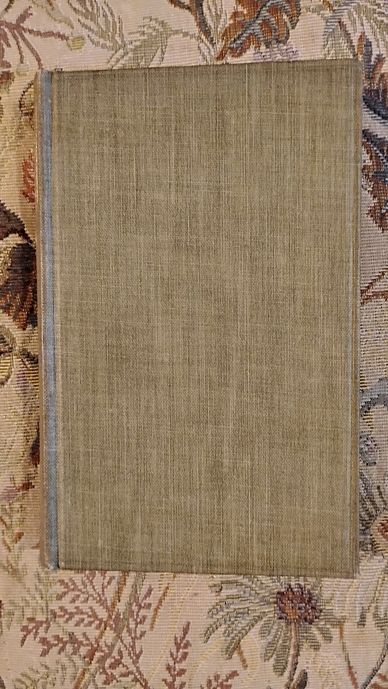 Old beige hardcover book on floral fabric.
