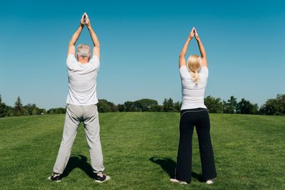 A man and woman stretching outdoors on a sunny day.