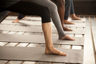 People practicing yoga barefoot on mats in a serene indoor setting.