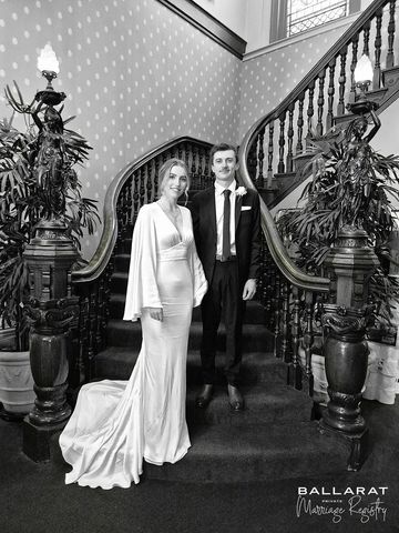 Bride and groom posing on a grand staircase in an elegant setting.