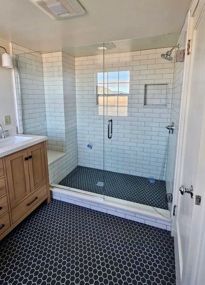 Modern bathroom with glass shower and hexagon tile flooring.
