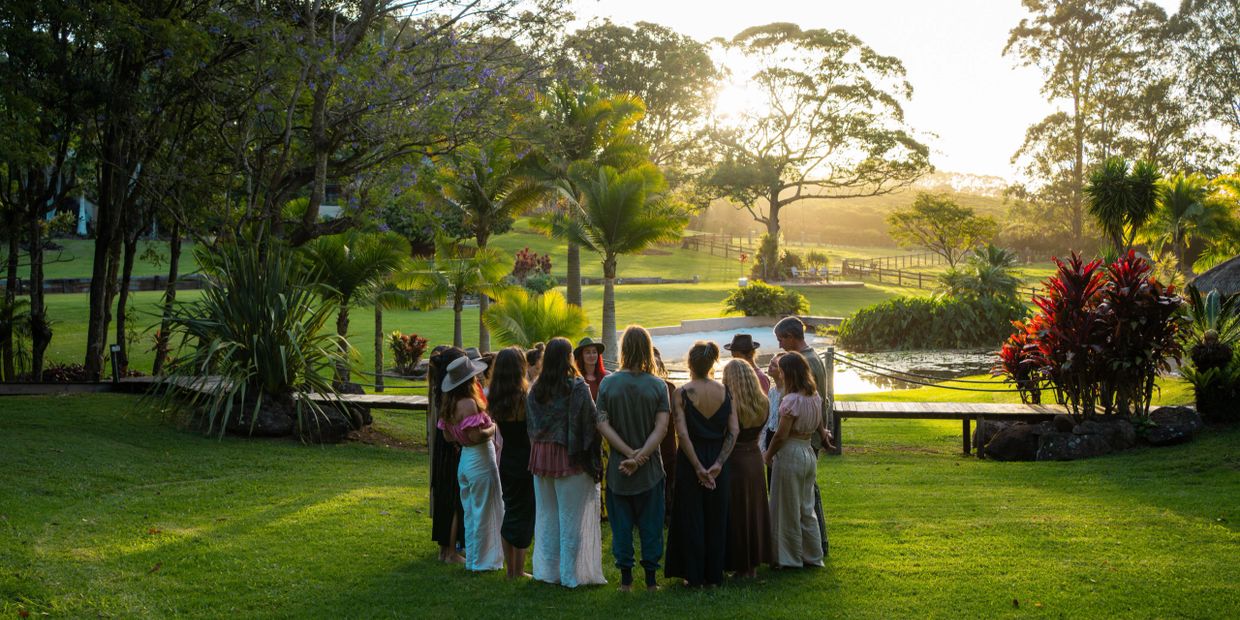 Group of people standing in a circle outdoors during sunset.
