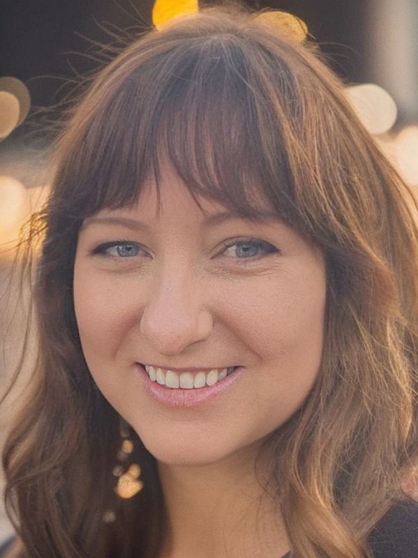 Close-up of a smiling woman with blue eyes and brown hair.