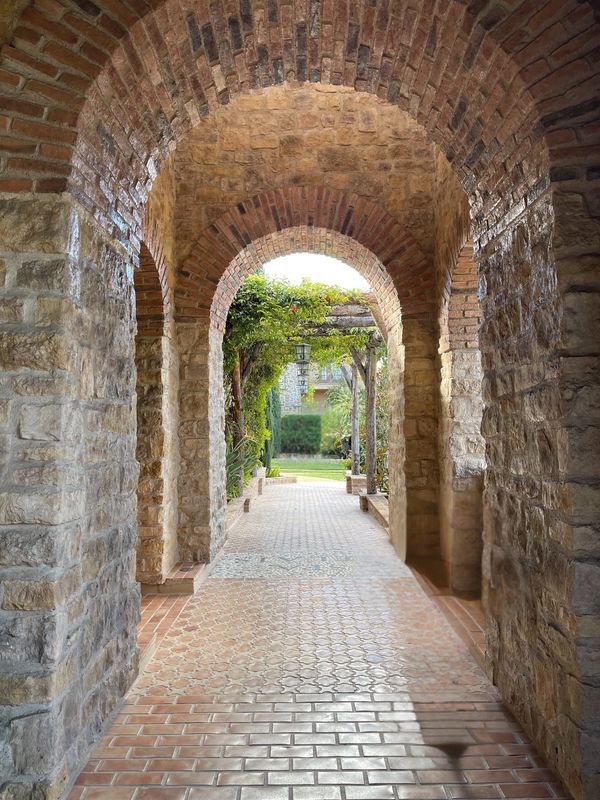 Stone and brick archway corridor leading to a garden area.