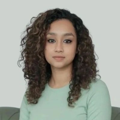 Young woman with curly hair wearing a light green top.