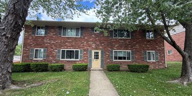 Two-story brick residential building with multiple windows and a central door.