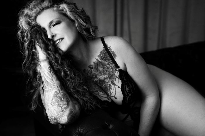 Tattooed woman smiling and posing sensually. 