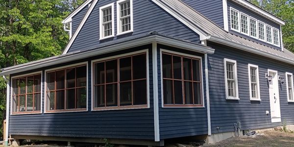 Blue wooden house with white trim and many windows.