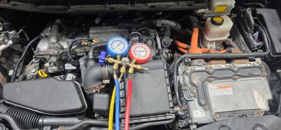 Car engine with HVAC gauges connected for air conditioning service.