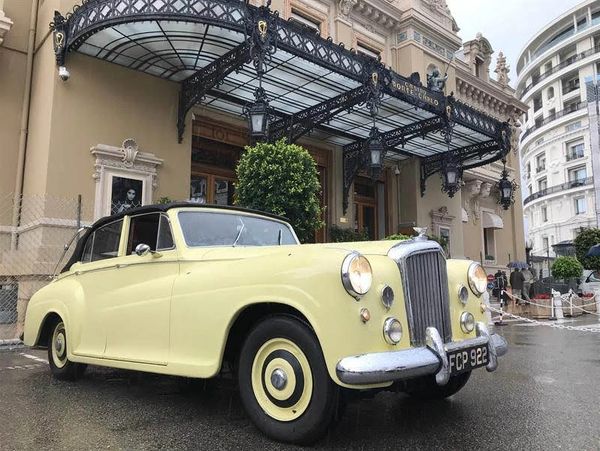 Fully restored vintage car in front of a hotel