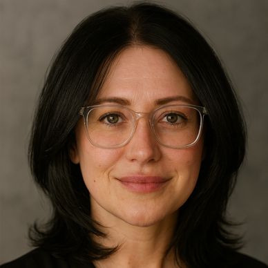 Portrait of a woman with glasses and dark hair smiling gently.