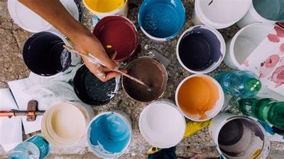 Hands mixing paint among various colorful paint buckets.