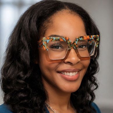 Smiling woman wearing large, colorful patterned glasses.