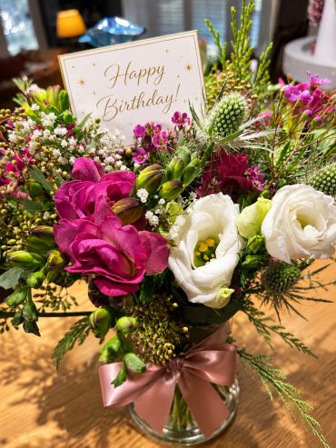 Colorful birthday flower bouquet with card and pink ribbon.