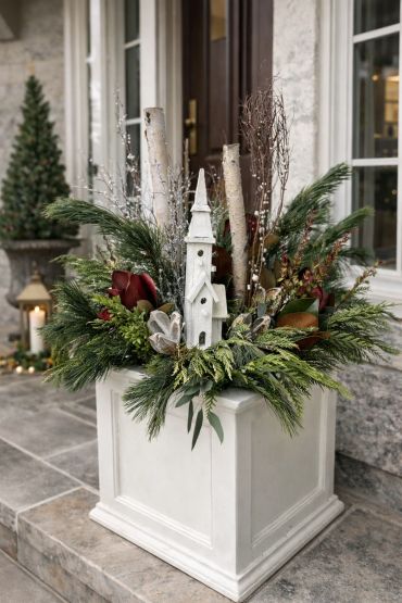 Decorative winter-themed planter with greenery and white church figurine.