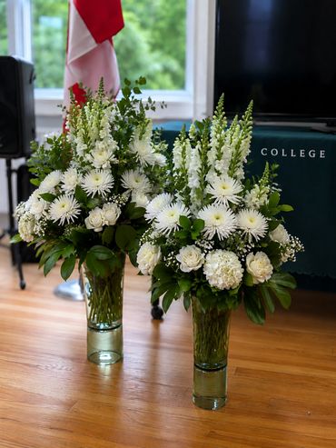 Two elegant white floral arrangements in glass vases.
